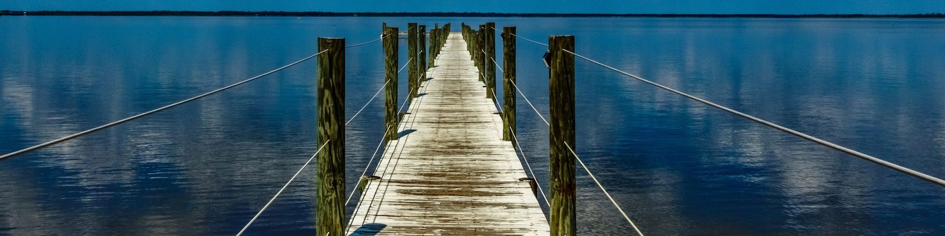 Un muelle de madera que se adentra en aguas tranquilas bajo un cielo despejado.