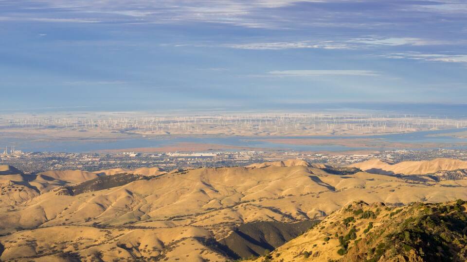 A mountainous landscape with a city in the distance.