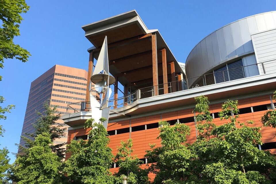 Un bâtiment moderne à la façade incurvée, entouré d’arbres verdoyants.