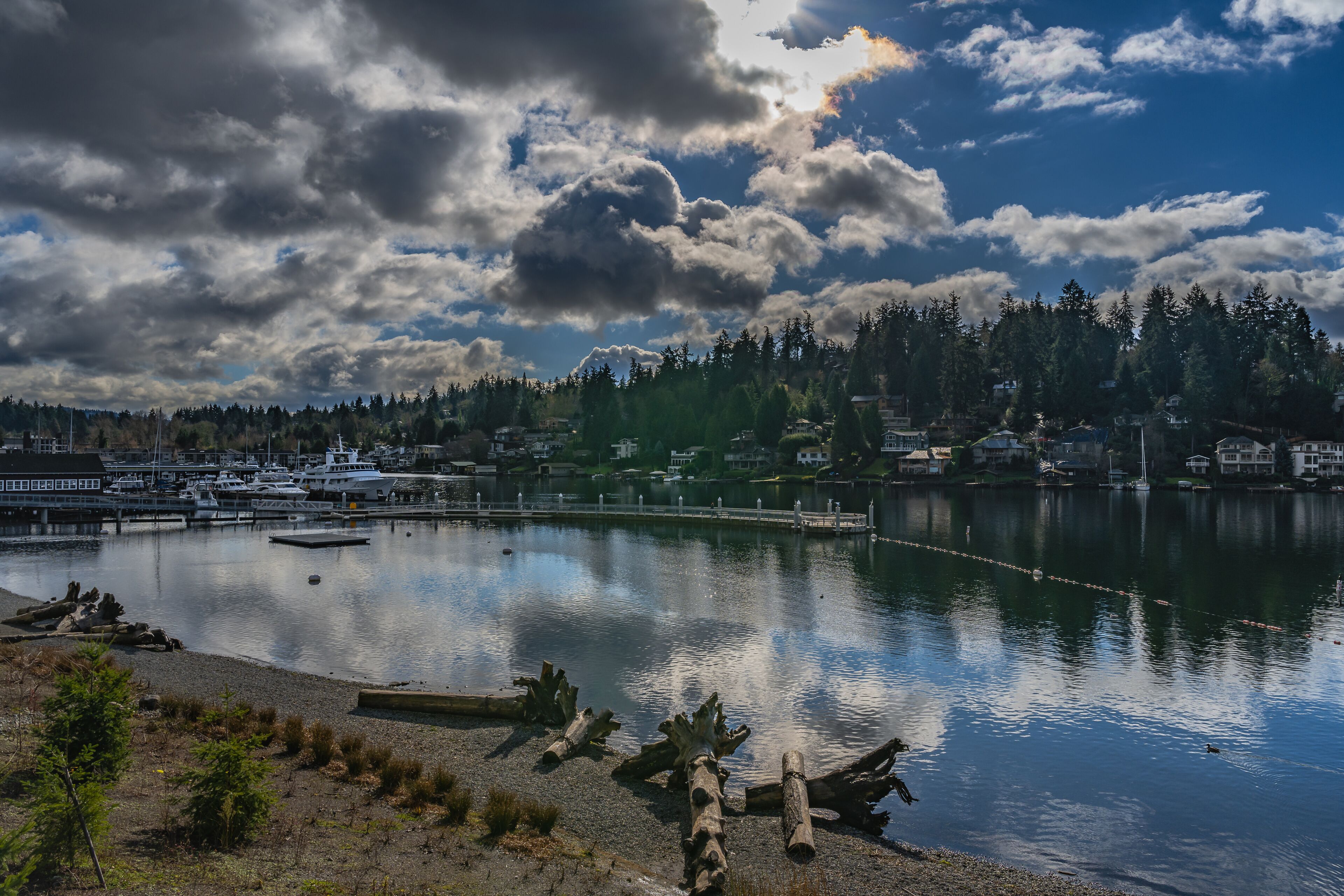 A calm lake with boats, a dock, and a forested shoreline.