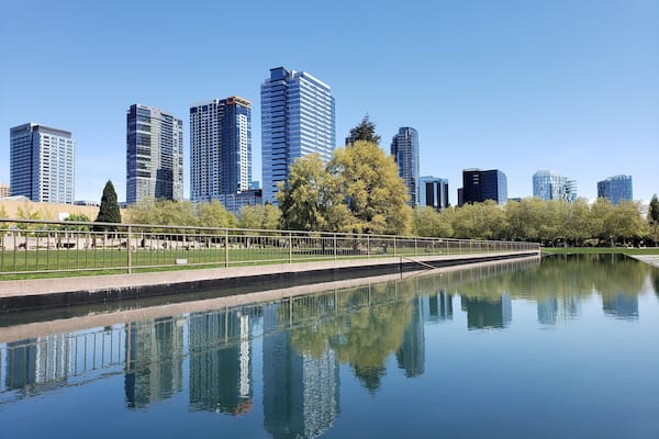 A cityscape with modern skyscrapers and a calm water body reflecting the buildings.