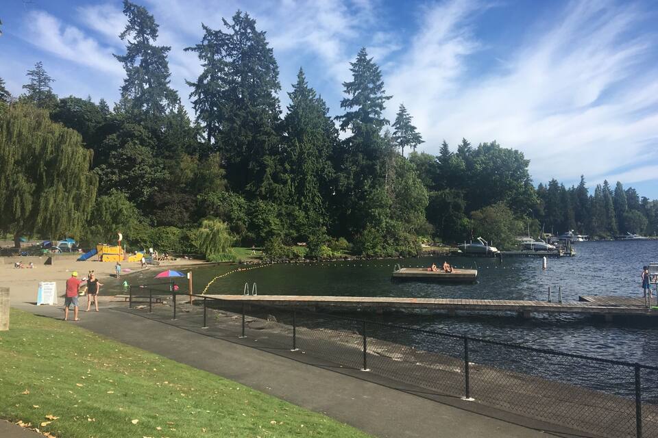 A lakeside park with a walking path, a playground, and a dock with boats.
