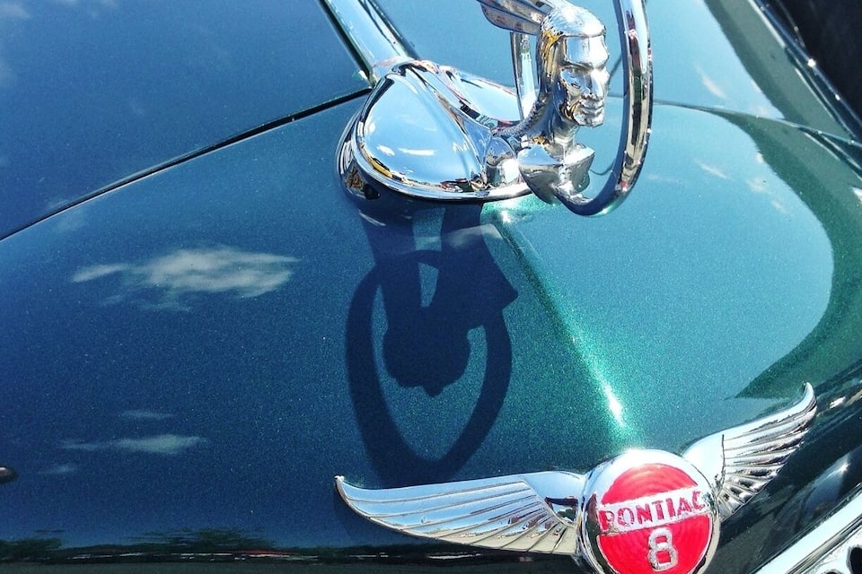 Primer plano del cofre de un automóvil con un emblema cromado y parrilla.