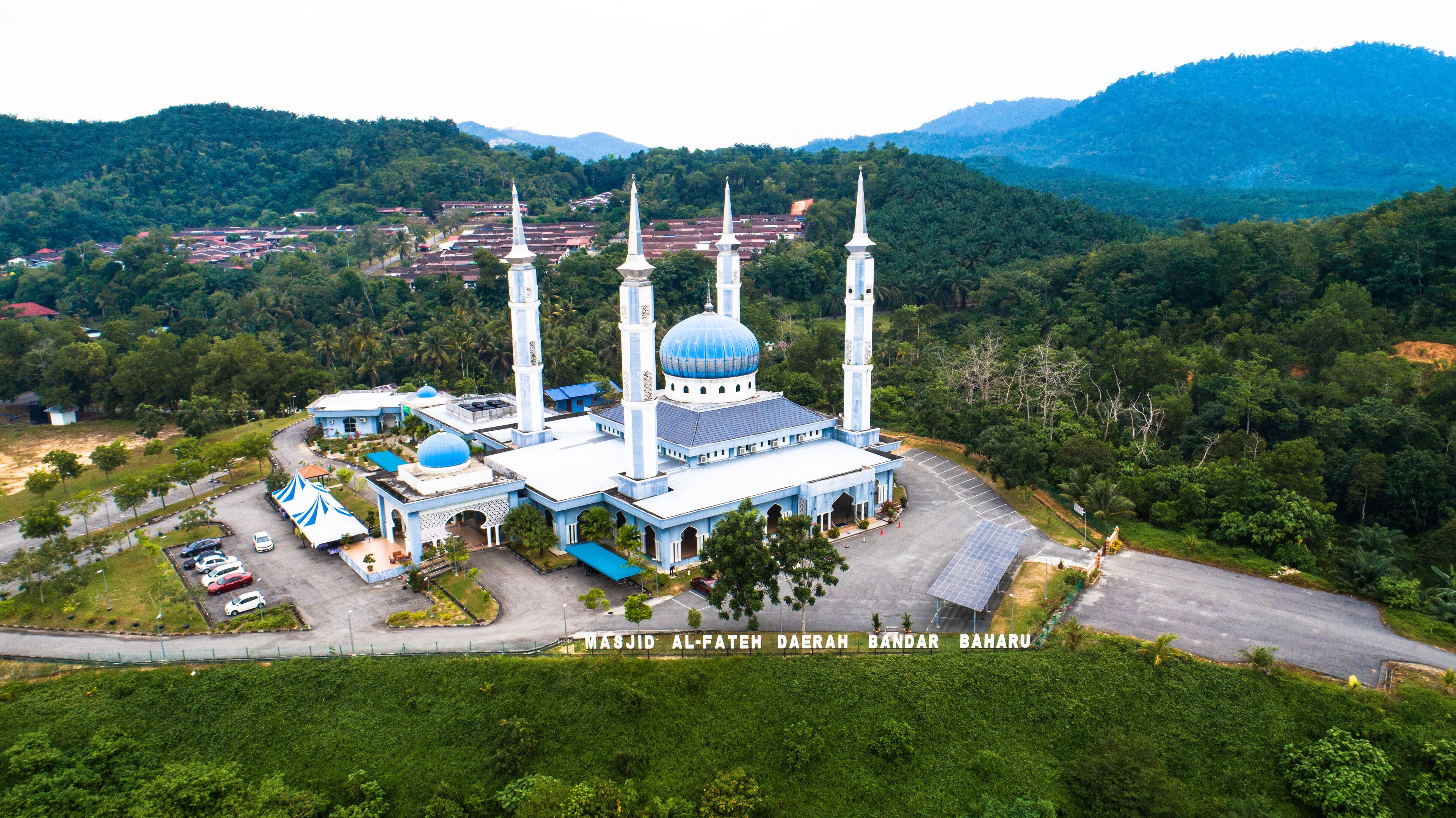 A mosque with a large dome and minarets, surrounded by lush greenery and hills.