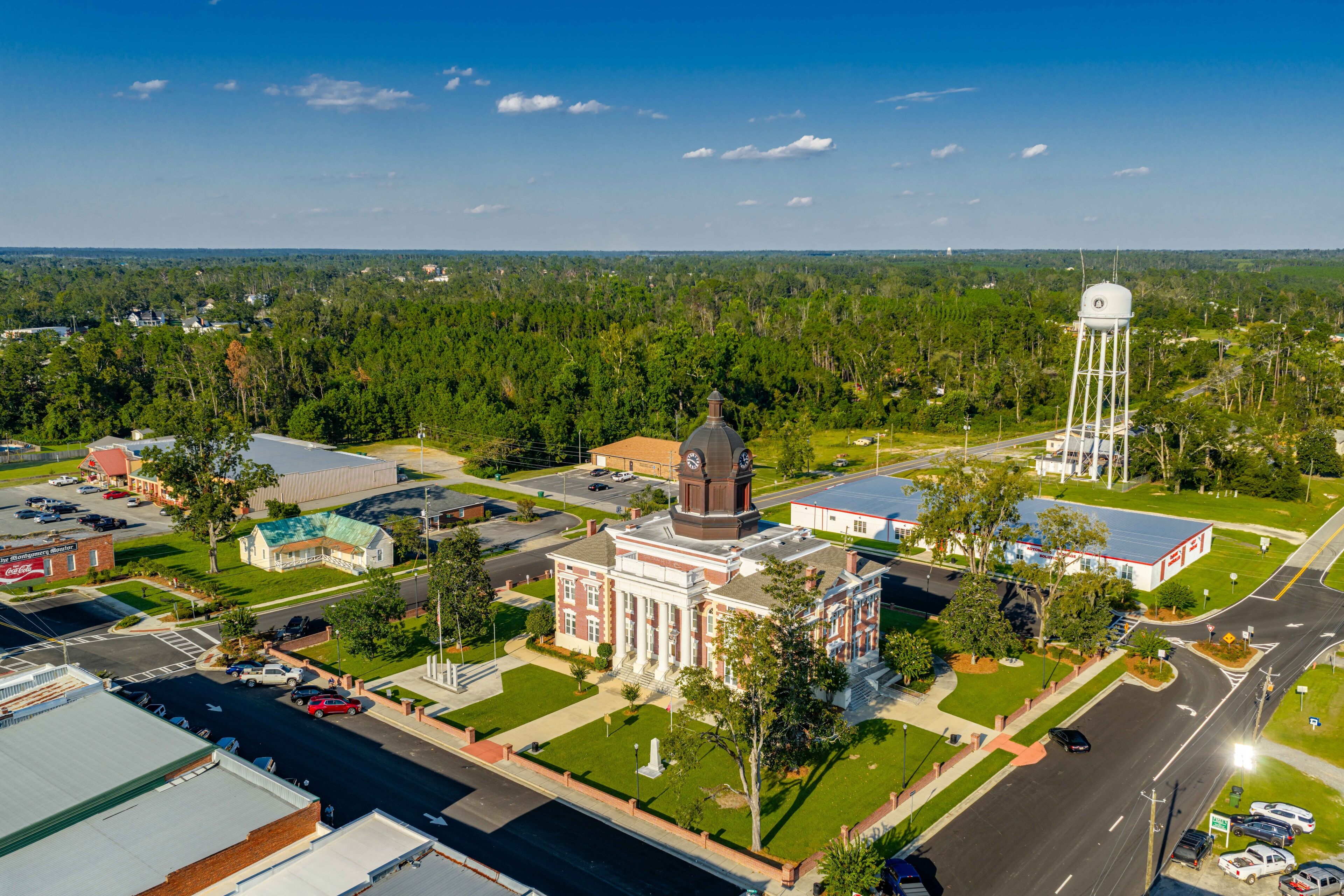 A town with a prominent clock tower, a large building with a dome, and a water tower.