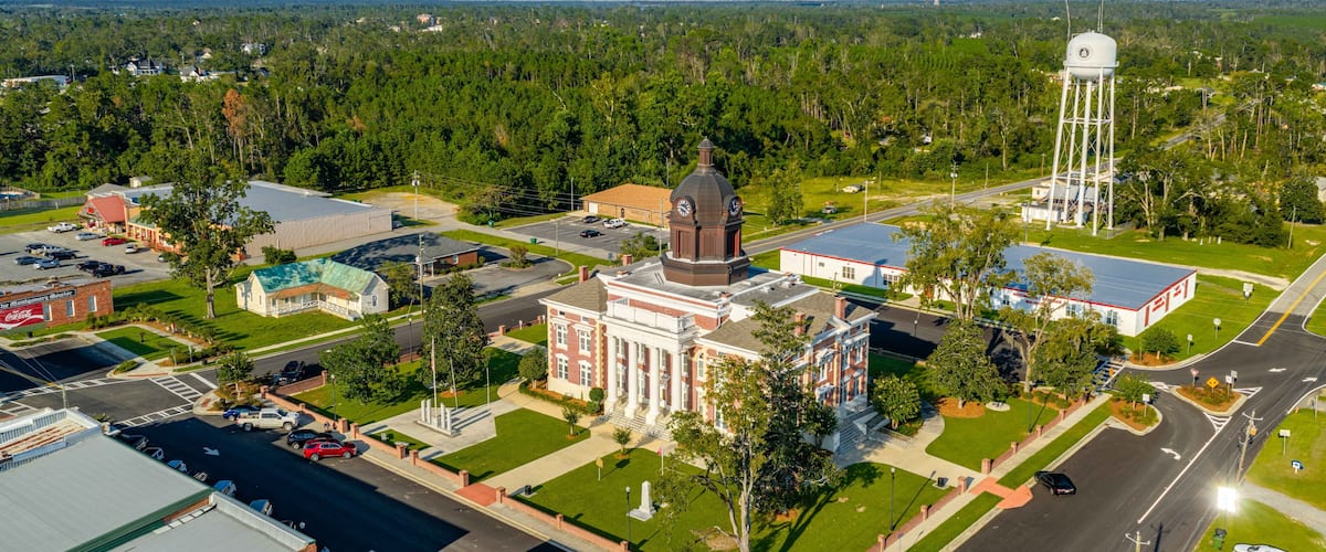A town with a prominent clock tower, a large building with a dome, and a water tower.