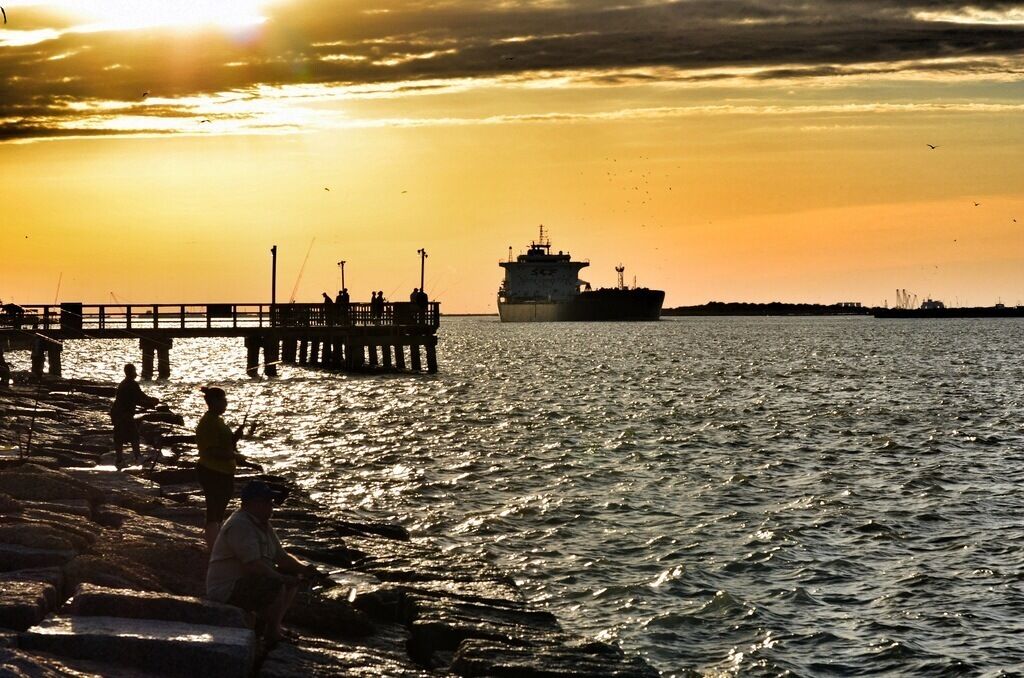 A view of Aransas Pass from the Port Aransas side. At sunset, go get a pizza and watch the ships pass through and dolphins swim nearby. So much to see, and a very relaxing spot. Stay until after dark so that you can hear the dolphins pop up for air in the nearby waters. It's also a great fishing spot.