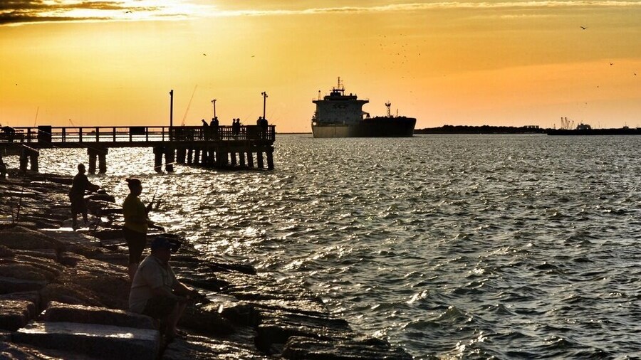A view of Aransas Pass from the Port Aransas side. At sunset, go get a pizza and watch the ships pass through and dolphins swim nearby. So much to see, and a very relaxing spot. Stay until after dark so that you can hear the dolphins pop up for air in the nearby waters. It's also a great fishing spot.