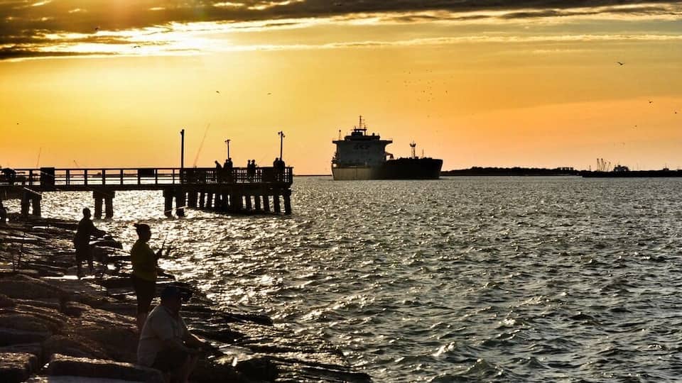 A view of Aransas Pass from the Port Aransas side. At sunset, go get a pizza and watch the ships pass through and dolphins swim nearby. So much to see, and a very relaxing spot. Stay until after dark so that you can hear the dolphins pop up for air in the nearby waters. It's also a great fishing spot.