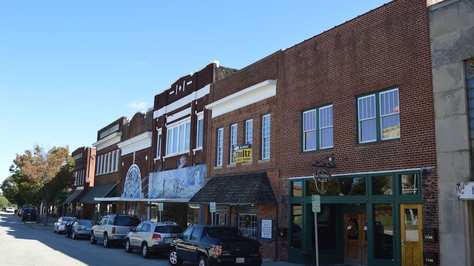 A street lined with brick buildings, including a restaurant and a gathering place.