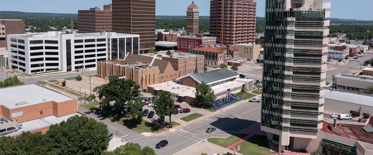 A cityscape with modern and historic buildings, a prominent tower, and a parking garage.