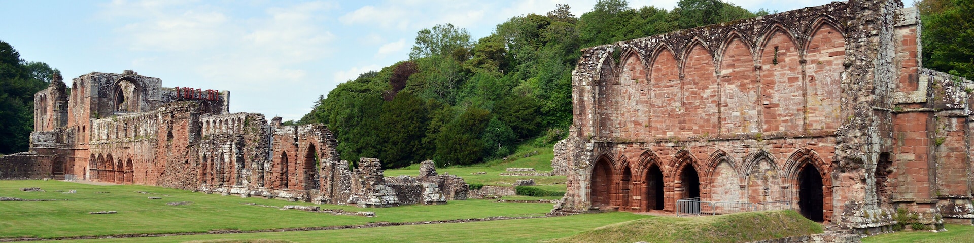Ancient ruins with arched doorways and a grassy field.