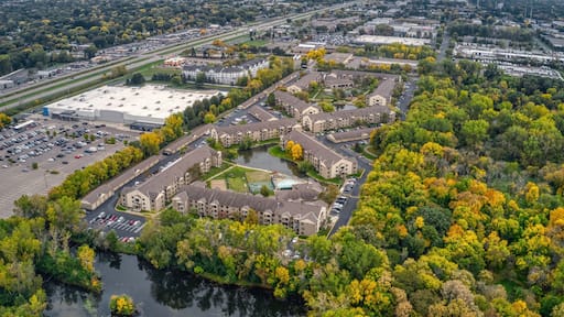 An aerial view of a residential area with apartment buildings, a parking lot, and a river.