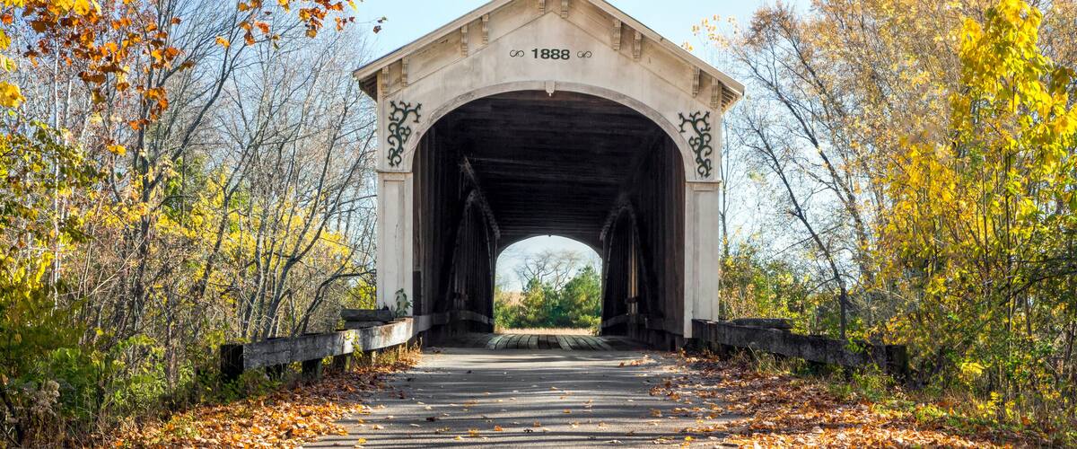 A covered bridge with the year 1888 marked on it, surrounded by autumn foliage.