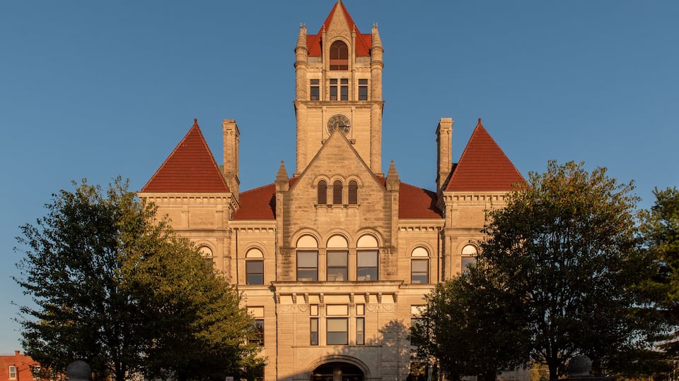 A large, historic building with a prominent tower and red-tiled roof.