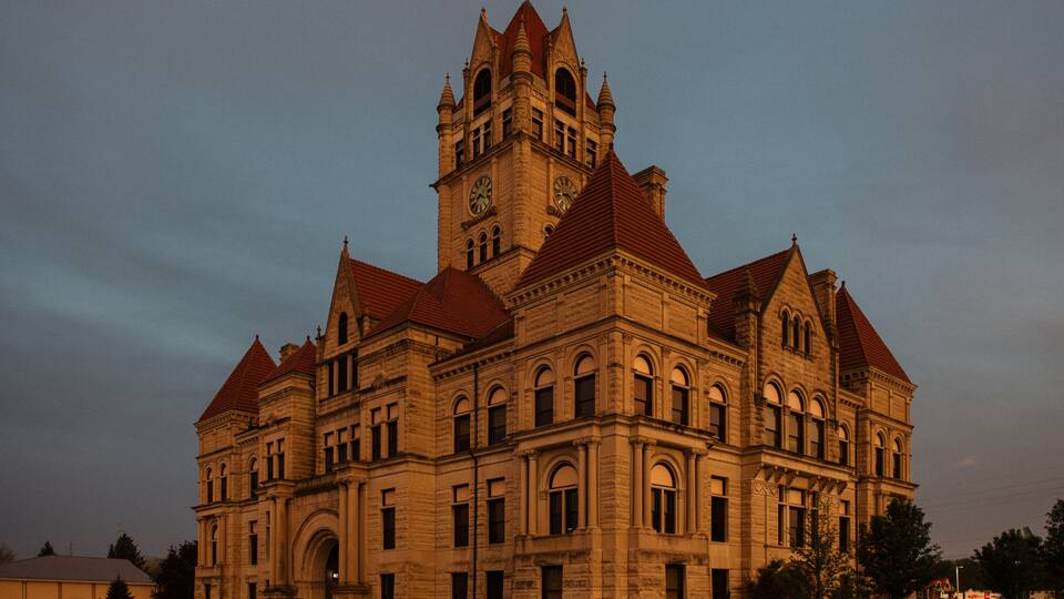 A large, historic building with a clock tower and red roofs.