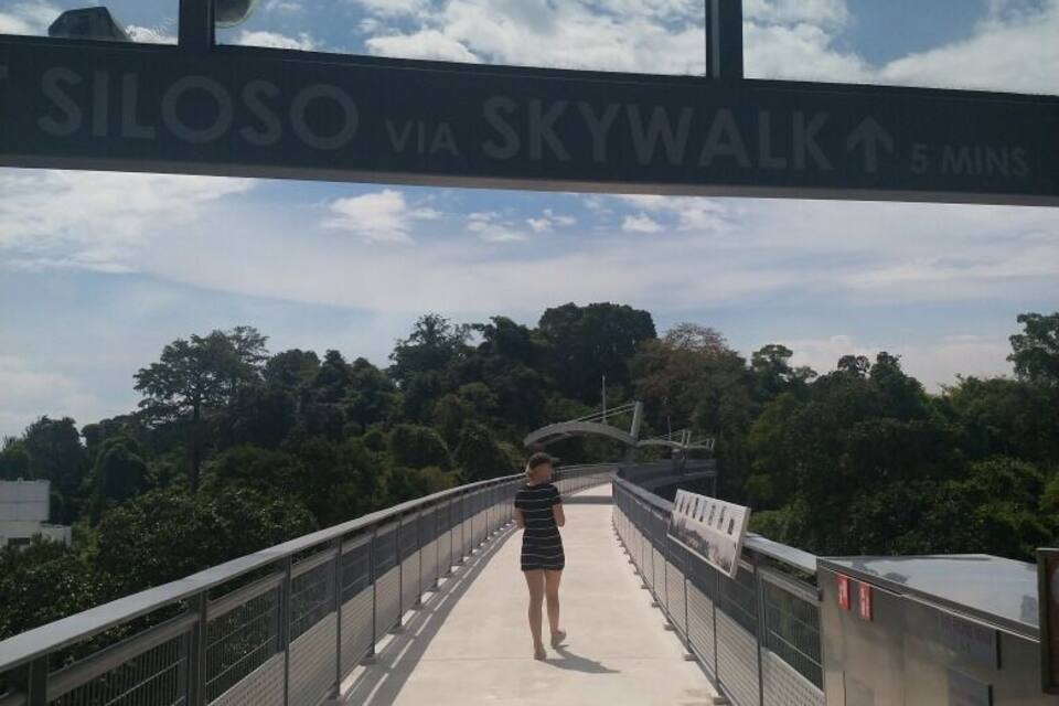 A pedestrian bridge with a sign reading "SILOSO VIA SKYWALK 5 MINS".