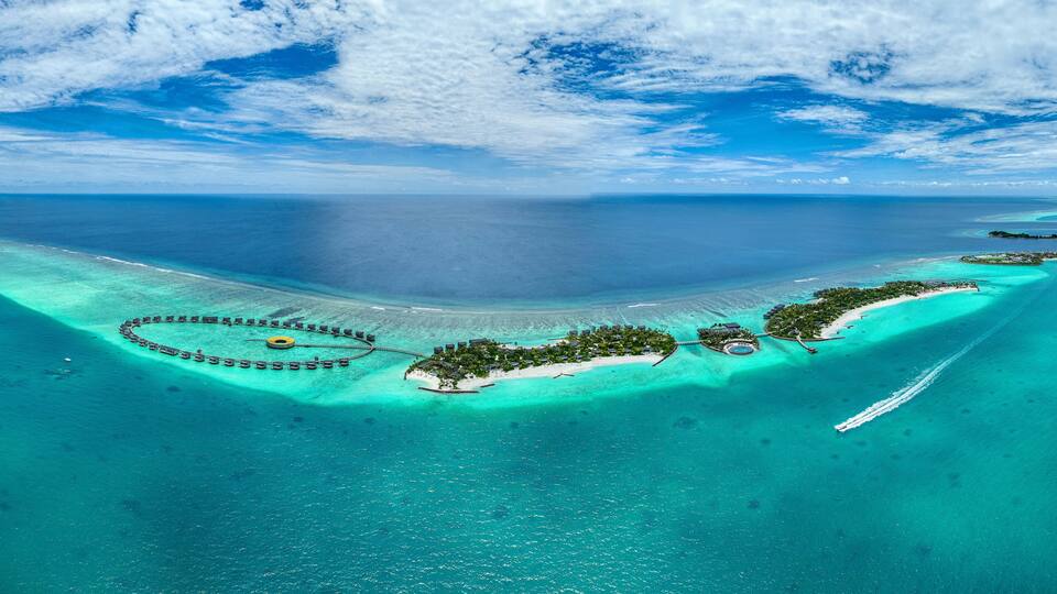 Panoramic aerial view of a boat sailing along the coast of Fari Island, Maldives.