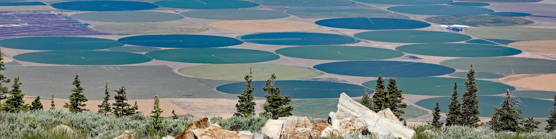 A vast landscape with numerous circular water bodies and a mountainous foreground with sparse vegetation and rocks.