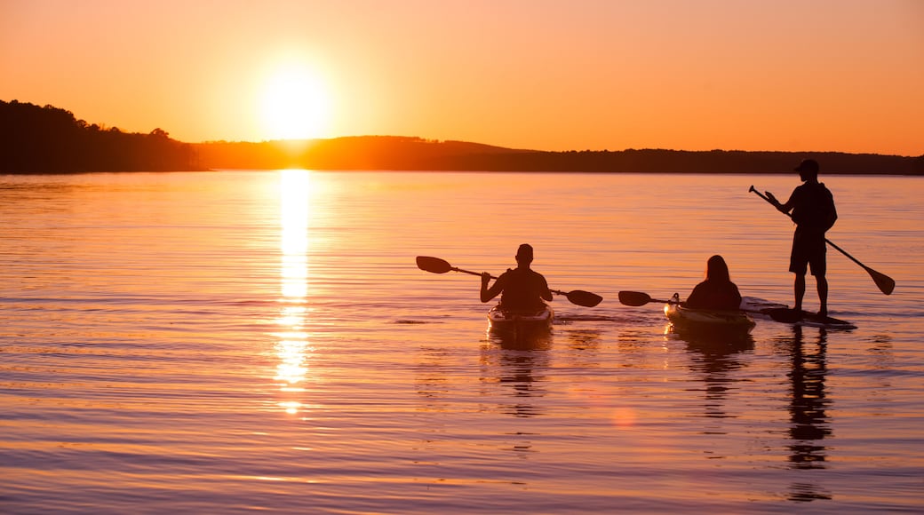 kayakers and stand up paddle boarder on lake at sunset