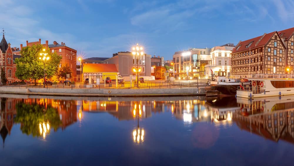 Panoramic view of Bydgoszcz waterfront at dusk, showing historic and modern buildings along the Brda River in Poland