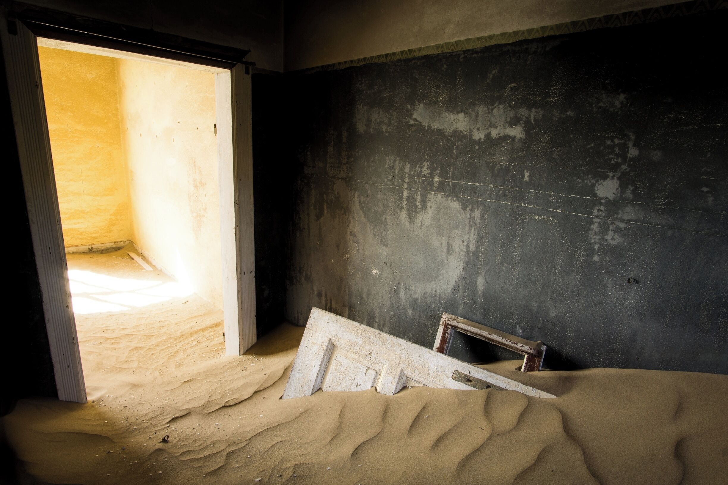 Kolmanskop is a ghost town located in Namibia. People there used to mine diamond, but they all left. The particularity of this ghost town is that the surrounding dunes (yes, this town is located straight in the middle of the desert !) are entering the house and make this place quite unique ! 
I would definitely recommend going there !
note : the place is only accessible in the morning, because it is way too windy in the afternoon, and it creates sandstorms. The site is only accessible from 8am to 12 but there are special permits for photographers to go there for sunrise or sunset.