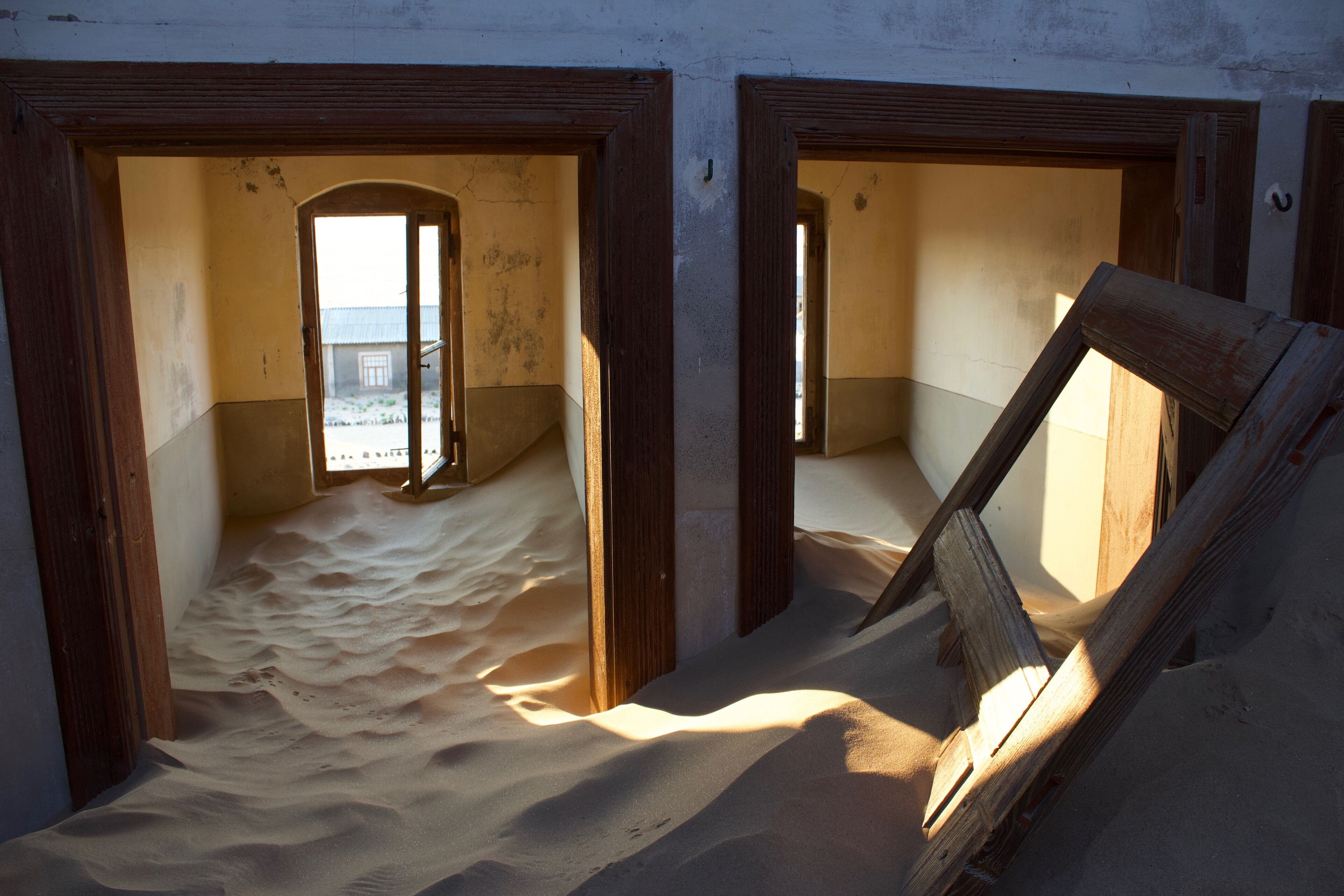 A room with sand on the floor and wooden door frames.