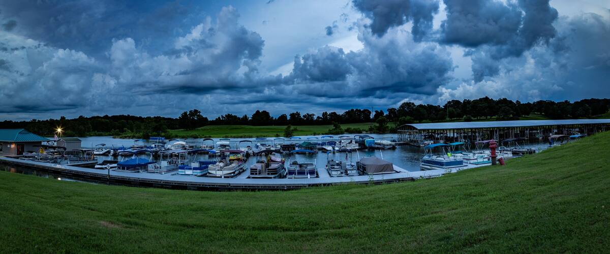 Boats and pontoons docked on Barren River Lake State Park Marina, Scottsville Kentucky during sunset with dramatic clouds over them.