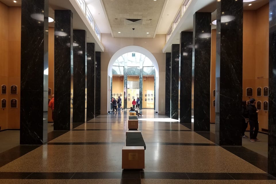 Um hall amplo com colunas de mármore, uma área de estar central e uma grande entrada em arco.