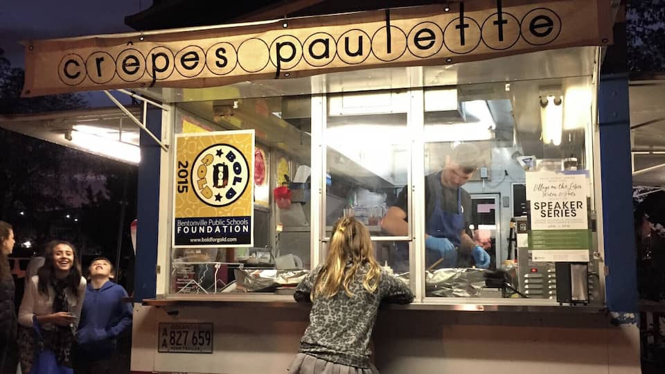 A crepe stand with a sign reading "crepes paullette" and a logo for Bentonville Public Schools Foundation.