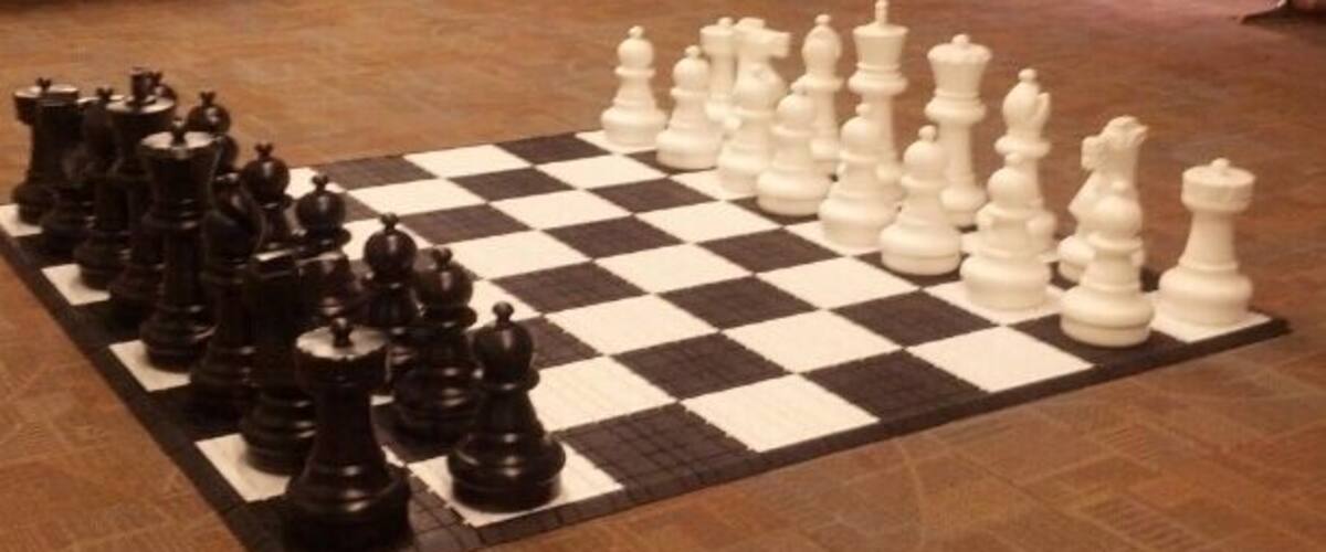 A large chessboard with pieces set up in an airport terminal.