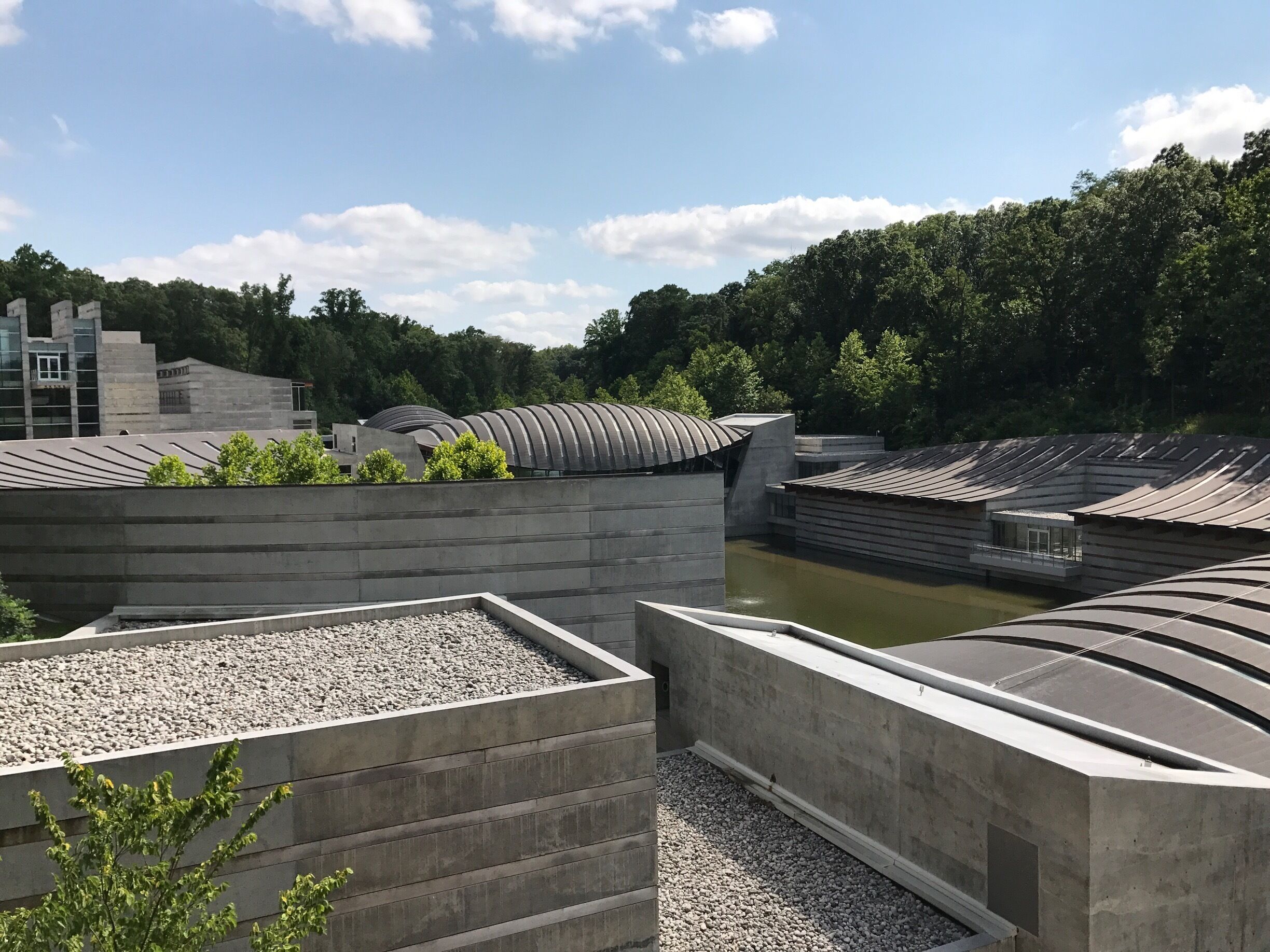 A modern architectural complex with curved roofs and a river in the background.