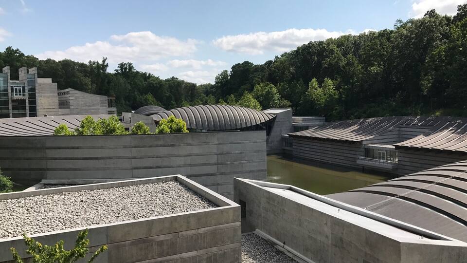 A modern architectural complex with curved roofs and a river in the background.