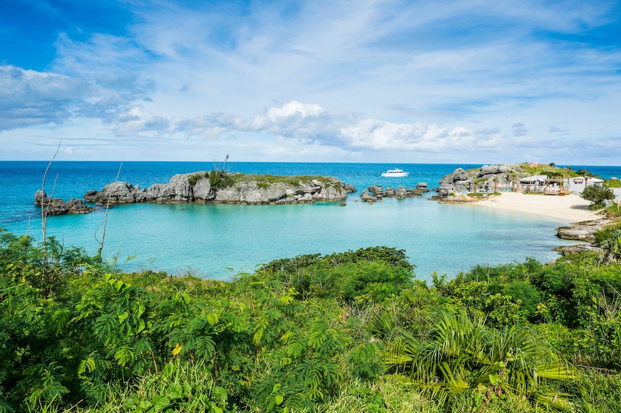 A coastal landscape with clear turquoise waters, rocky outcrops, and lush greenery.