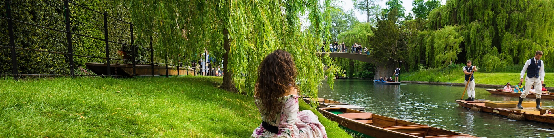 Un río con barcos, un sauce y una orilla cubierta de hierba.