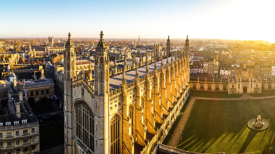 A cathedral with intricate Gothic architecture, a large open square, and a distant church spire.