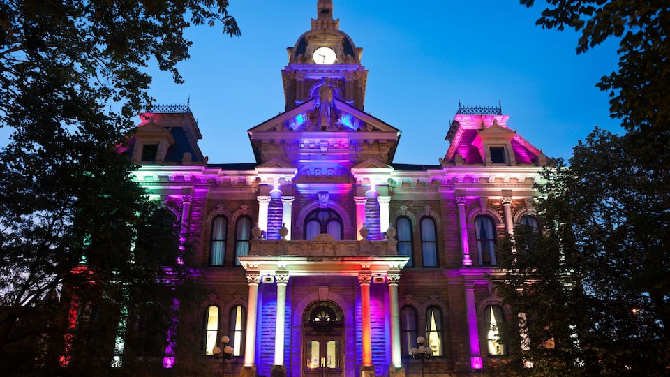 A historic building with illuminated columns and a clock tower at dusk.
