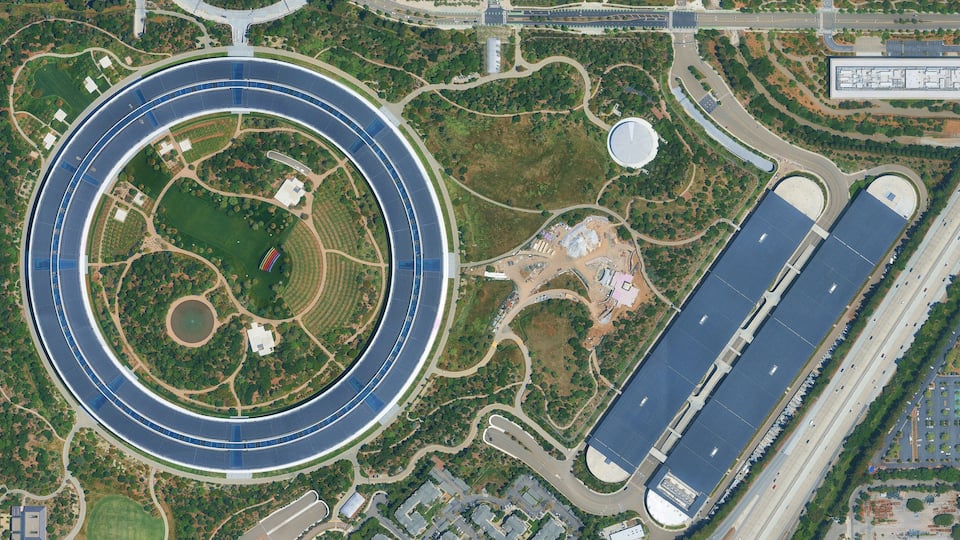 A circular solar farm surrounded by roads and greenery.