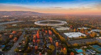 An aerial view of a cityscape with a distinctive circular building, residential areas, and autumn foliage.