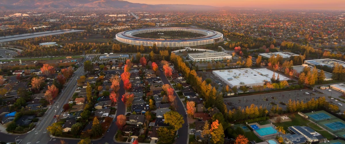 An aerial view of a cityscape with a distinctive circular building, residential areas, and autumn foliage.