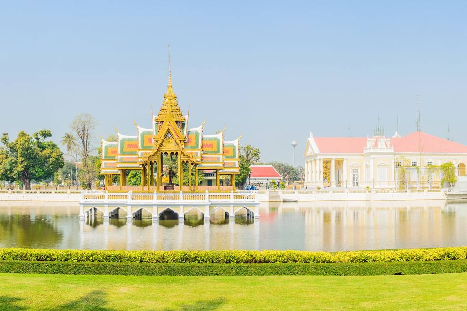A temple with a golden spire, a white building with arched windows, and a lotus pond.