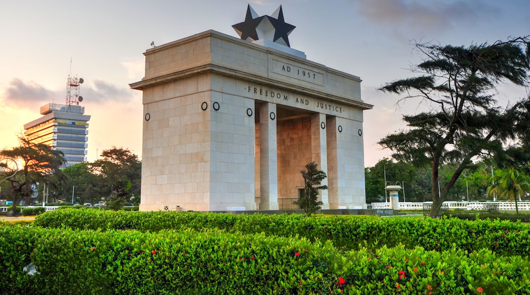 Un monumento con inscripciones 'AD 1957' y 'FREEDOM AND JUSTICE', coronado por dos estrellas, rodeado de follaje.