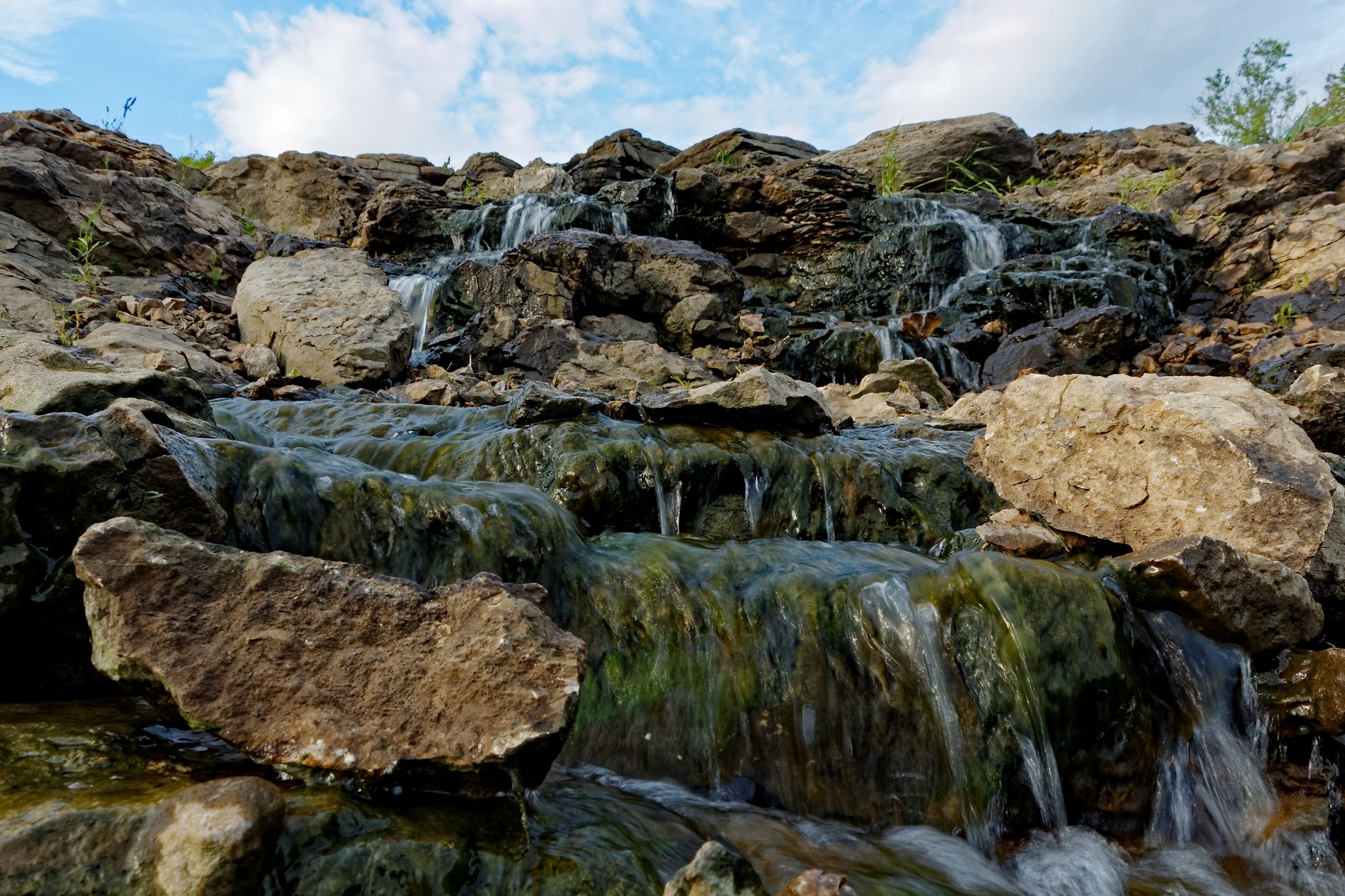 The water rushes over the Lake MacBride Waterfall. This waterfall has several main falls and numerous smaller falls.