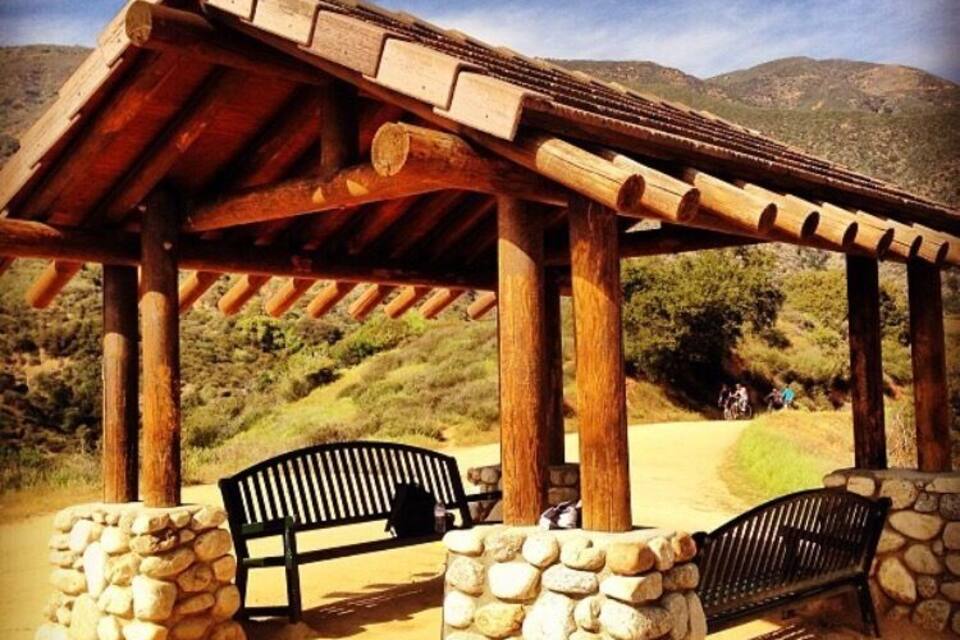 A wooden pergola with benches in a desert landscape.
