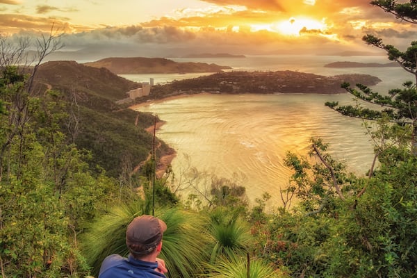 After a hike up Passage Peak on Hamilton Island, a walker rests and watches the sunset