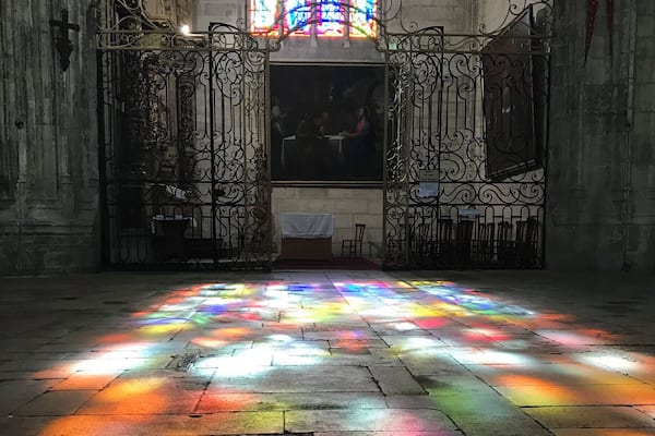 A stained glass window casting colorful light on the floor.
