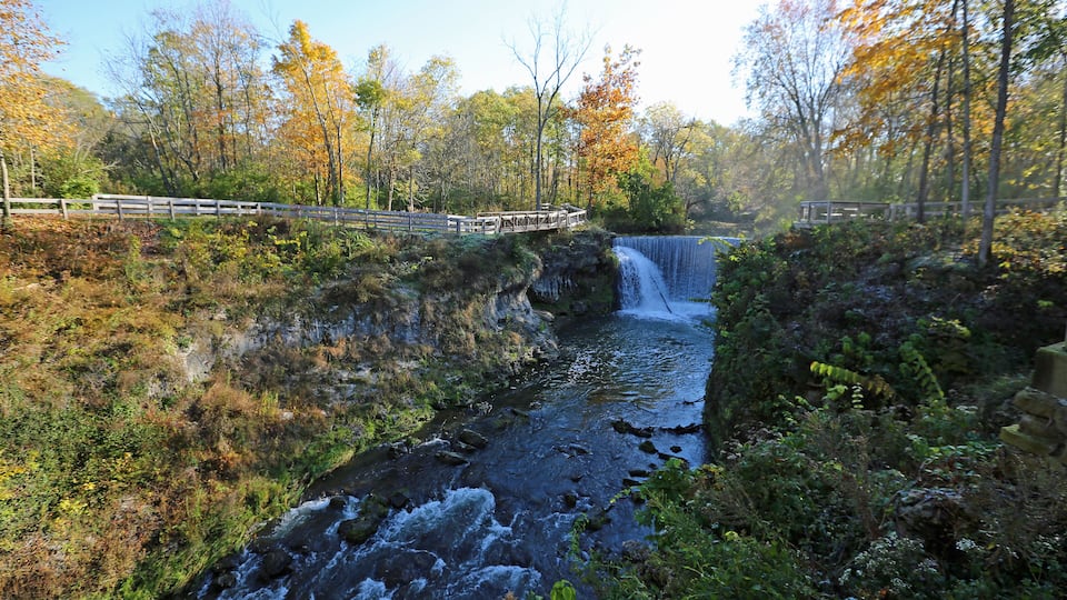 A waterfall in a forested area with wooden walkways.