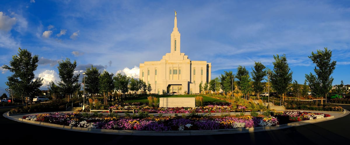 A large building with a tall spire, surrounded by a landscaped garden with various colorful flowers.