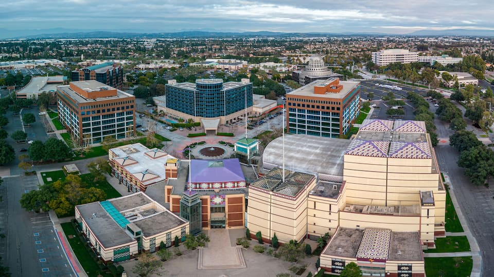 An aerial view of a cityscape with modern buildings, a central plaza, and surrounding greenery.