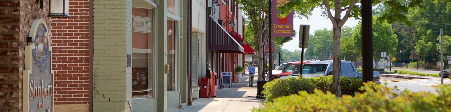 A street lined with brick buildings, a red car parked on the side, and a 'Downtown Commerce' sign.